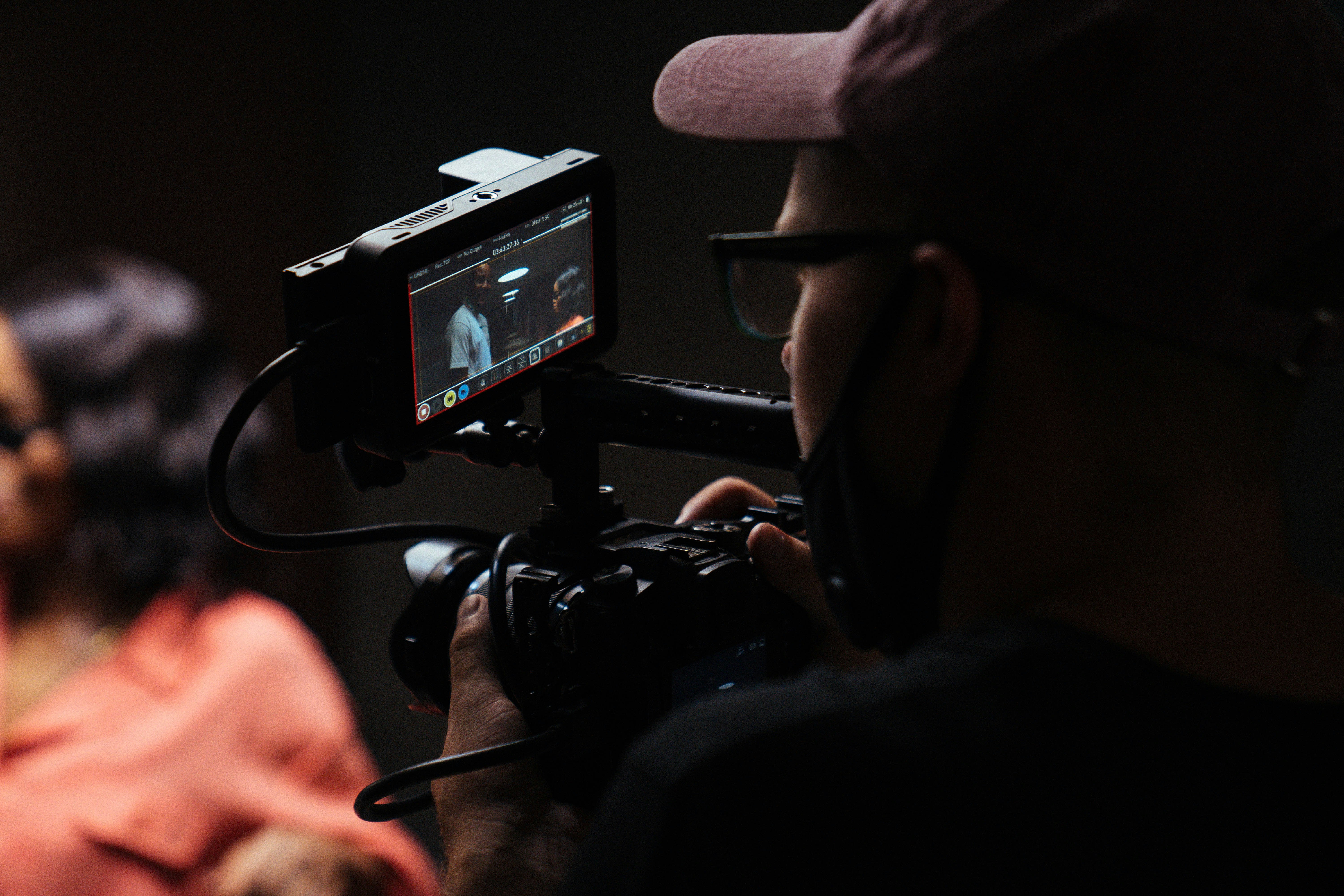 man in black hat holding black video camera